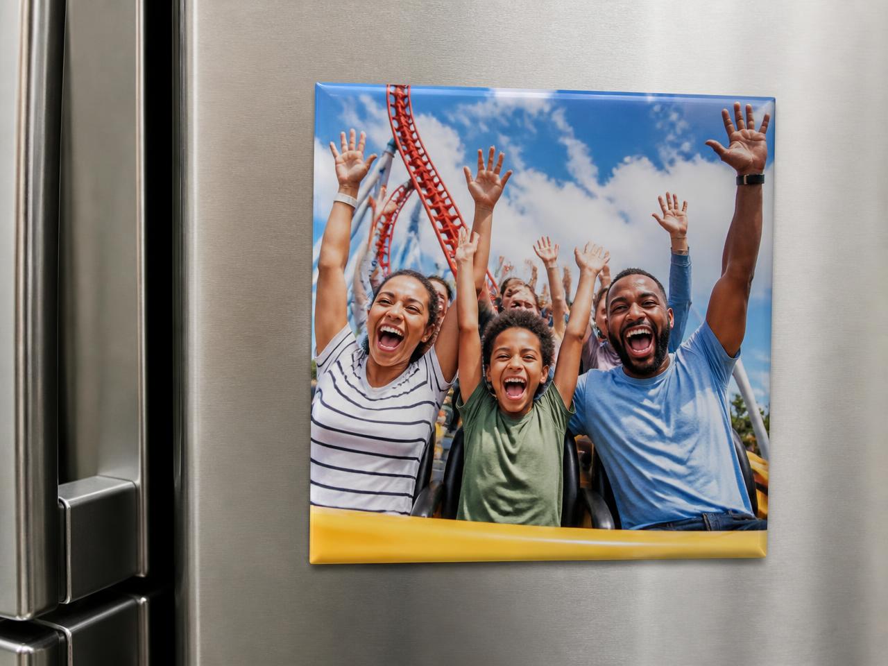 Square photo magnet showing a family with hands up riding a roller coaster, on a stainless steel fridge